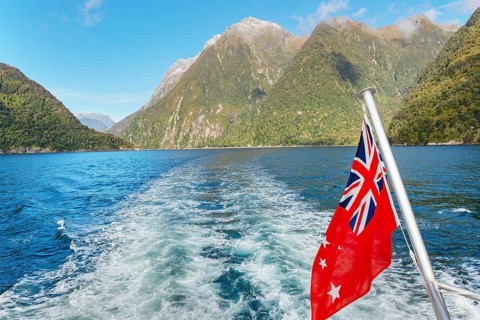 New Zealand flag waving, Milford Sound, South Island, Southland, New Zealand, Australasia, Oceania