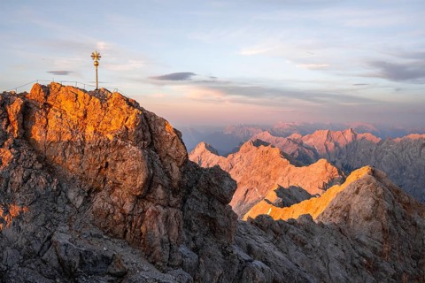 Summit of the Zugspitze with golden summit cross, alpenglow at sunset, Northern Limestone Alps,