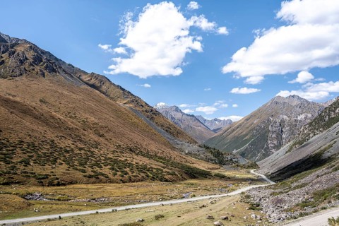 Gravel track in a valley, picturesque mountain landscape with white mountain peaks, Tian Shan