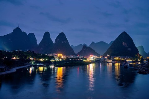View of Yangshuo town illuminated in the evening with dramatic karst mountain landscape in