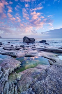 Rocks on beach of fjord of Norwegian sea in winteron sunset. Utakliev beach, Lofoten islands,