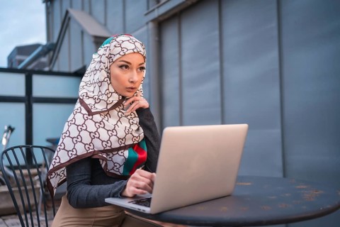 Arab girl with a white veil at the computer on the terrace of a coffe shop, contrabass with the