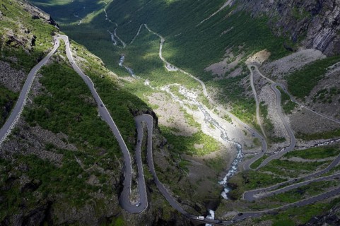 A winding road meanders through a green valley between steep mountains, Trollstigen, Andalsnes,