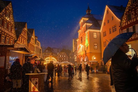 People with umbrellas strolling through the Christmas-lit old town market at night, Christmas