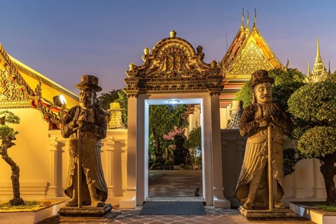 Huge Farang Guard fortifications at the entrance to the Buddhist temple Wat Pho at dusk, Bangkok,