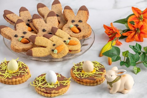 Bunny biscuits with carrots and egg decoration next to orange flowers and Easter bunny