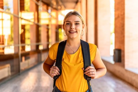 Portrait of blonde university student smiling at camera standing on the campus