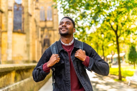 African man smiling while exploring walking down a city