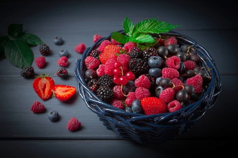 Mix of fresh berries, in a basket, on a wooden gray table, no people, top view