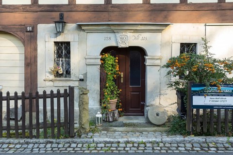 Historic door frame and loving decoration with millstone and flowers in front of a typical