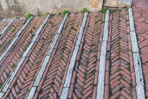Brick-paved slope in the cathedral square in the medieval town of San Gimignano, province of Siena,