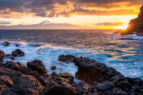 Sunrise on the beach at San Marcos. Rocks, sea and the sun. Tenerife and the Teide in the