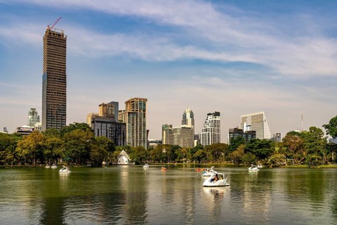 Swan pedal boat on Lumphini Lake in Lumphini Park and the skyline of Bangkok, Thailand, Asia
