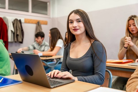 Young woman using laptop in university classroom, participating in an engaging lesson with her