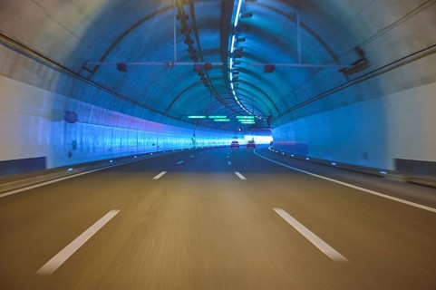 Modern, well-lit motorway tunnel with blue illuminated walls and a clear asphalt road, Zurich,