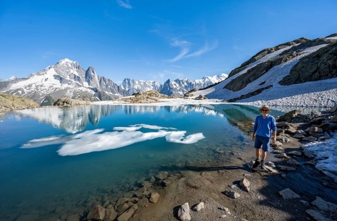 Mountaineer in front of mountain landscape with mountain lake, tourist at Lac Blanc with water