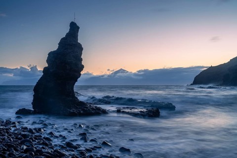 Before sunrise on the beach at Playa de La Caleta. Rocks and sea. Tenerife and the Teide in the