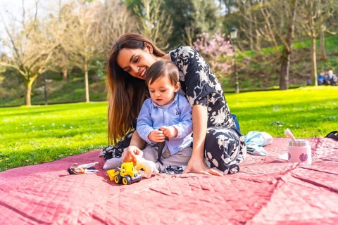 Mother and baby enjoying quality time together, playing with toys during a sunny picnic in a park