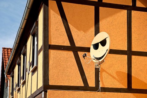Satellite dish with smiley on a house wall in Langenstein, Halberstadt, Saxony-Anhalt, Germany,