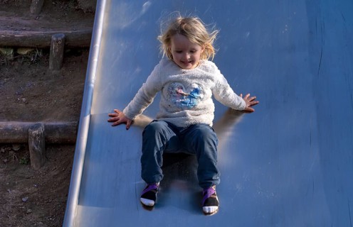 Little girl, 3 years, blonde, jumper, Disney, Elsa, ice queen, slides on slide, playground,