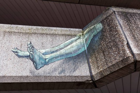 Human legs protruding from a concrete façade, surreal graffiti on the Seidenweberhaus,
