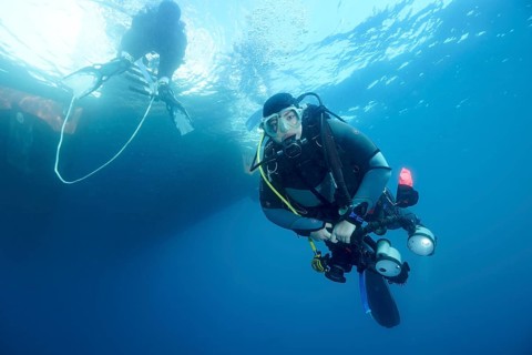 Diver under water with complete equipment waiting until the ladder back to the dive boat is free,