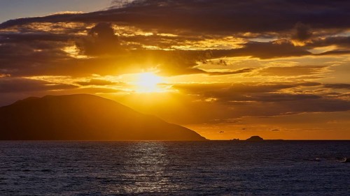 Dramatic golden sunset over the sea with clouds and an island in the background, sunset, Kassos,