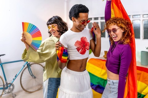 Happy multi-ethnic and gender diverse friends celebrating pride party at home wearing sunglasses