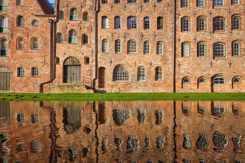 Historic salt storehouse, brick building with windows and doors, reflection on the water surface of