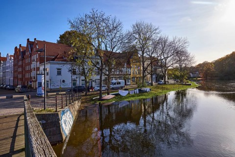 Riverbank of the Trave, pedestrian bridge Dankwartsbrücke, trees, historic houses, reflections on