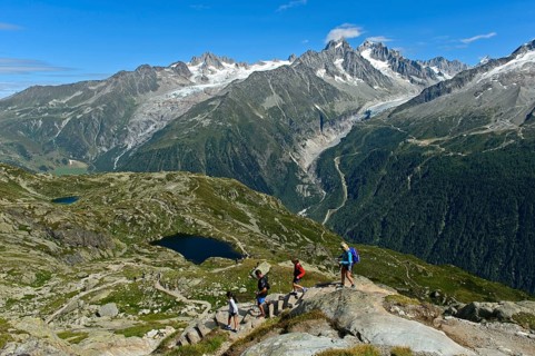Hikers in the Chamonix hiking area in front of the alpine panorama of the French Alps, from left to
