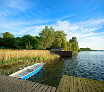 Wooden jetty in the reeds, rowing boat and boathouses, Schaalsee Biosphere Reserve, Zarrentin am
