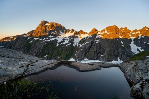 Rocky mountain peaks, small pond in moorland at Trollfjord Hytta, mountain landscape with alpenglow