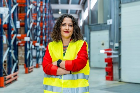 Portrait of a female worker in a distribution warehouse wearing safety waistcoat looking proud