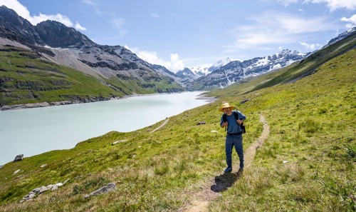 Mountaineer on a hiking trail at a blue mountain lake, Lac des Dix reservoir, Valais Alps, Valais,
