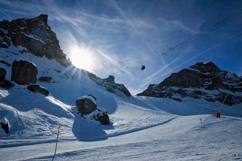View of a ski resort piste with people skiing in Dolomites in Italy with cable car ski lift. Ski