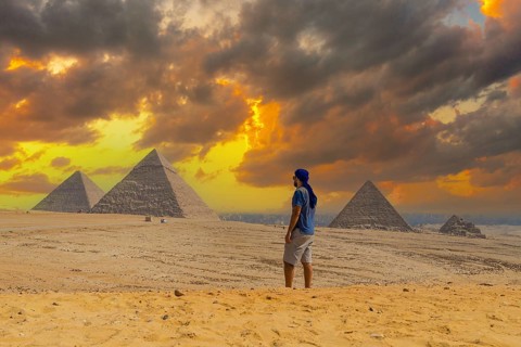 A young man in a blue turban walking next to the Pyramids of Giza, the oldest Funerary monument in