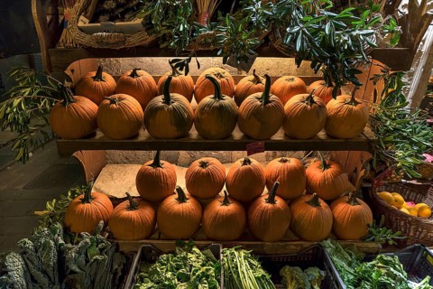 Shelves of Hokkaido pumpkins in front of a fruit shop open at night in the historic centre, Genoa,