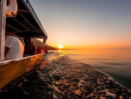 View from below along the orange sunset water of Shkoder Lake in Shiroka from a tourist boat.