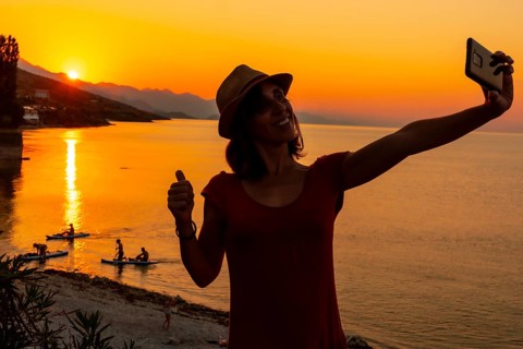 Silhouette of a woman taking a selfie at sunset at Shkoder lake in Shiroka municipality, summer