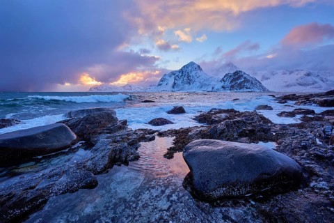 Beach of Norwegian sea on rocky coast in fjord on sunset in winter. Vareid beach, Lofoten islands,