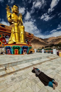Tibetan Buddhist woman worshiping and praying Buddha Maitreya statue in Likir gompa (monastery),