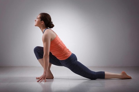 Beautiful sporty fit yogini woman practices yoga asana Anjaneyasana, low crescent lunge pose in