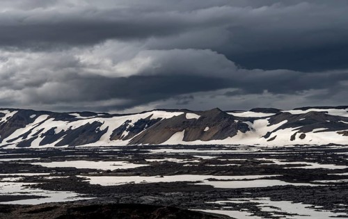 Snow-covered volcanic landscape with volcanic sand and petrified lava, crater of Askja volcano,