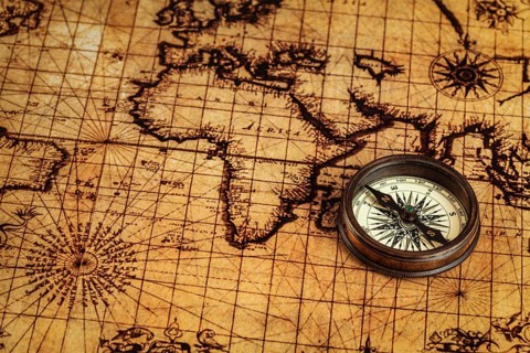 Travel geography navigation concept background, old vintage retro compass on ancient world map