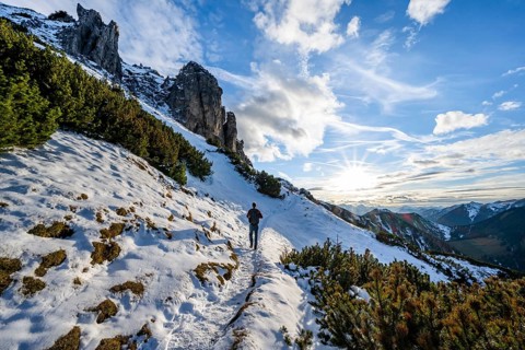 Hikers on a hiking trail with snow, sun star, ascent to Kramerspitz, in autumn, Ammergau Alps,