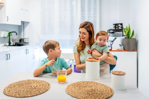 Mother with baby having breakfast with schoolboy at home before going to school