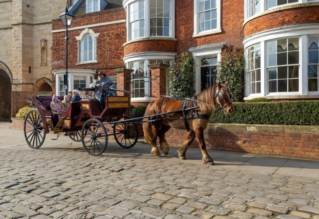 Horse and carriage ride passing houses in Minster Yard of Lincoln cathedral, city of Lincoln,