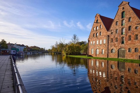 Historic salt warehouses with reflections on the water surface, morning light, Liebesbrücke,