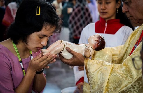 Archbishop John Moolachira holds an idol of baby Jesus Christ as devotees kiss the idol during a